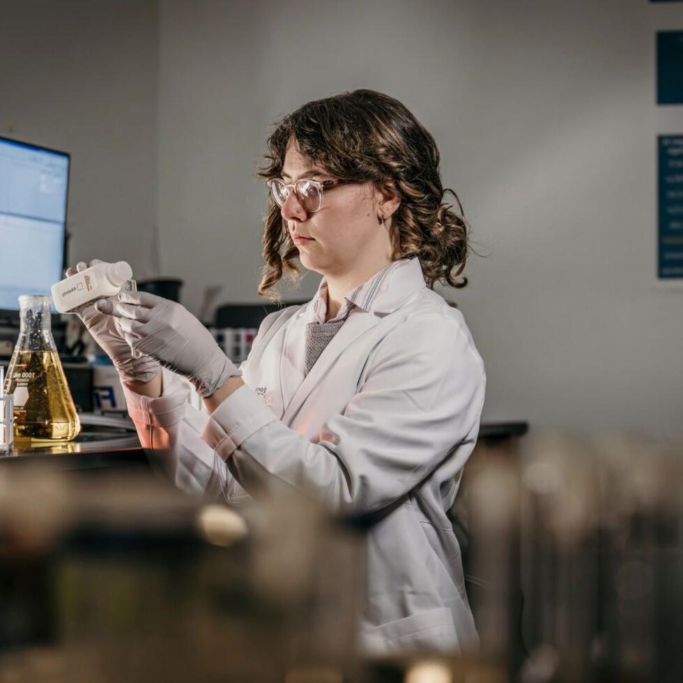 A student holding beakers in a science lab